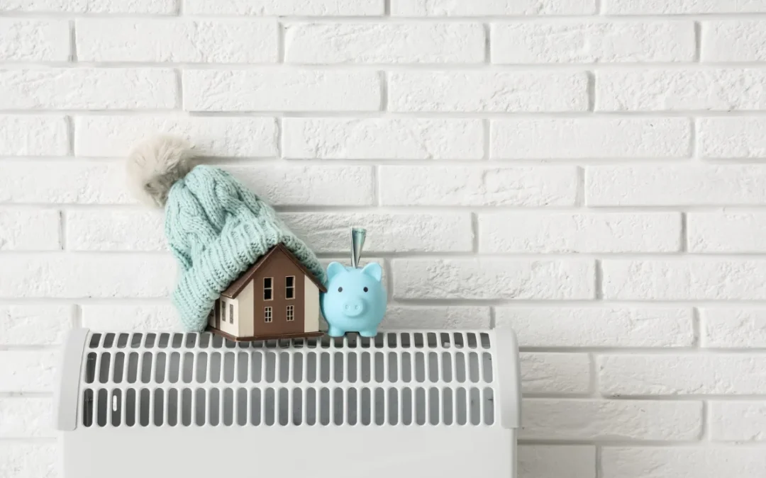 Radiador con casa con gorro de lana y hucha de cerdito, representando ahorro energético gracias al aislamiento térmico.